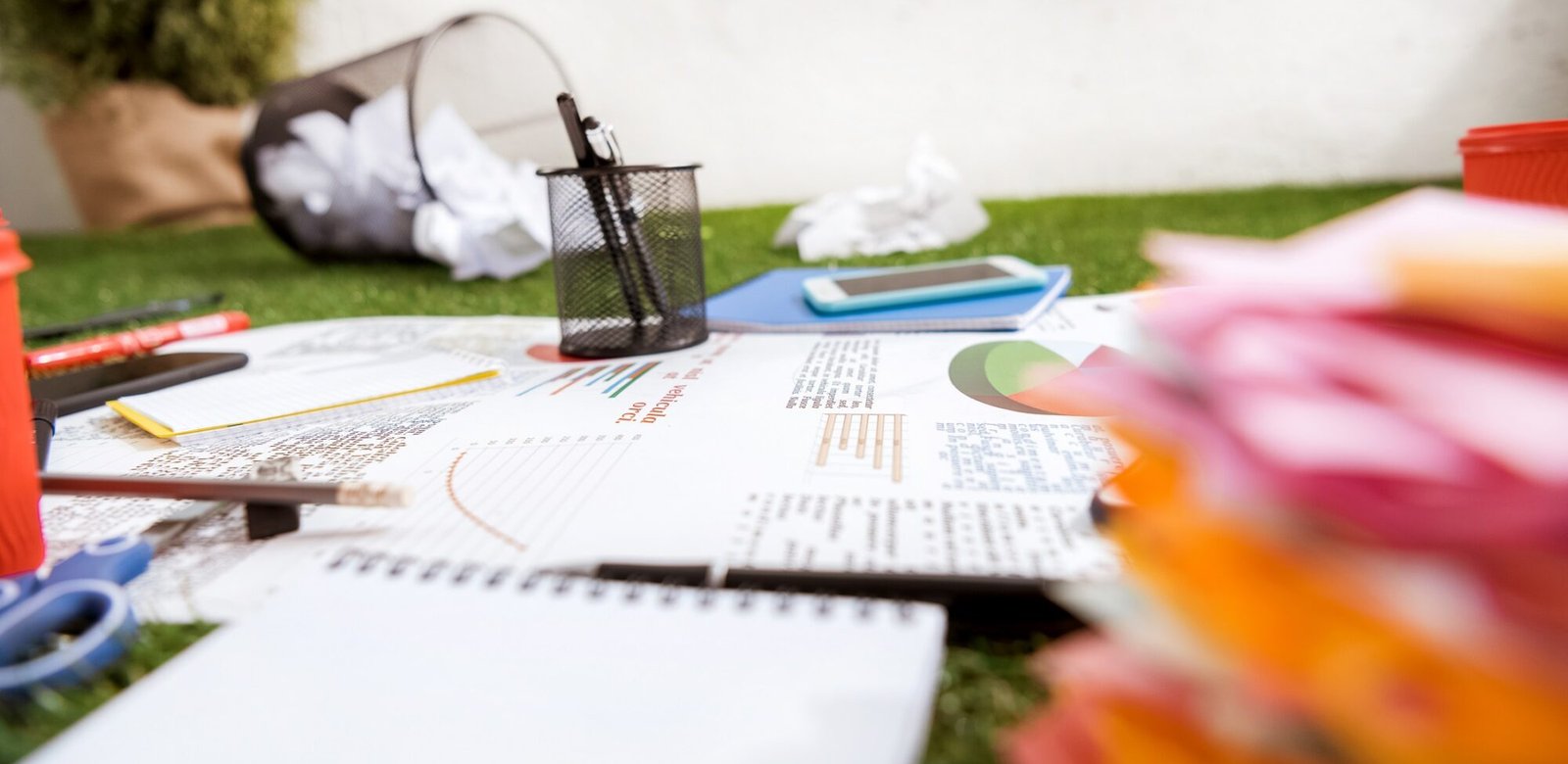 heap of business objects and office supplies laying on green grass carpet at office, business